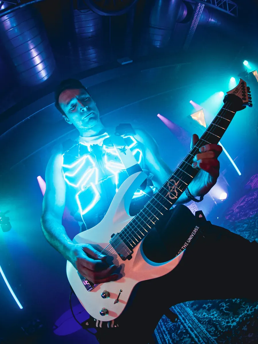 Gitarrist mit leuchtender cyan Weste und weisser Gitarre von unten