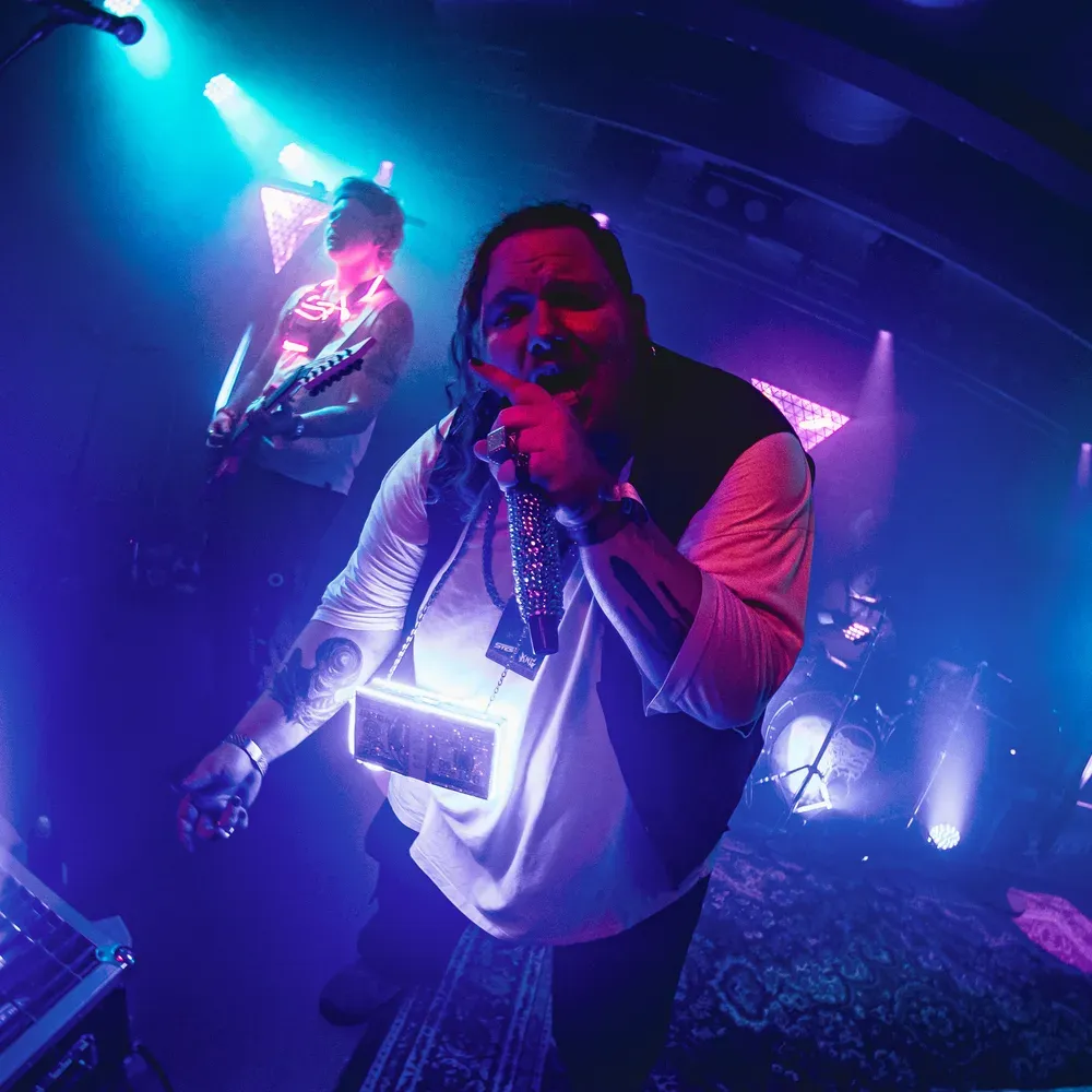 Saenger und Bassist performen zusammen im cyan-blauen Licht